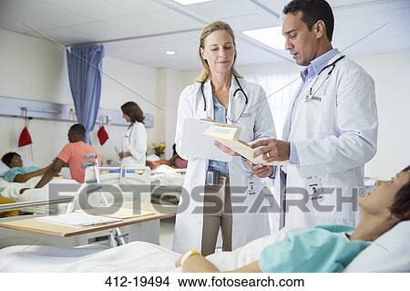 Picture - Doctors talking to patient in hospital room. Fotosearch
