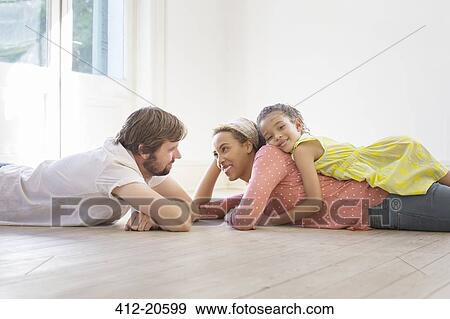 Family laying on the ground together in living space View Large Photo Image Stock Photo - Family laying on the ground together in living space . Fotosearch