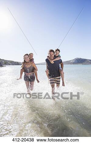 Family running in water on beach View Large Photo Image Stock Photo - Family running in water on beach. Fotosearch