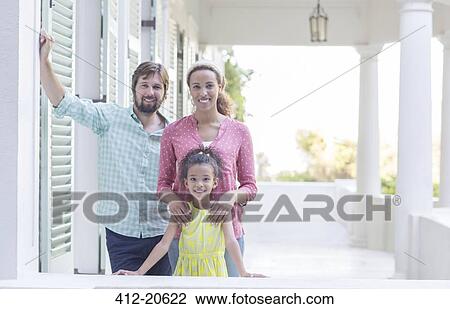 Stock Image - Family smiling on porch together. Fotosearch