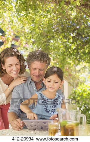 Grand parents playing on digital tablet with granddaughter  View Large Photo Image Picture - Grand parents playing on digital tablet with granddaughter . Fotosearch