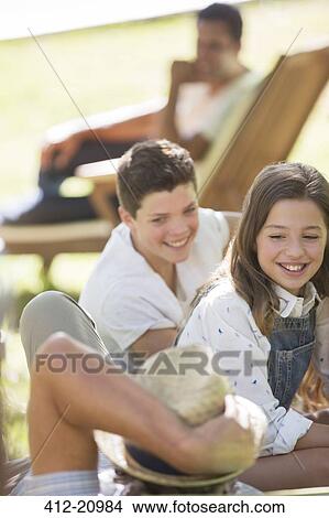 Picture - Grandchildren relaxing with Grandfather outdoors. Fotosearch