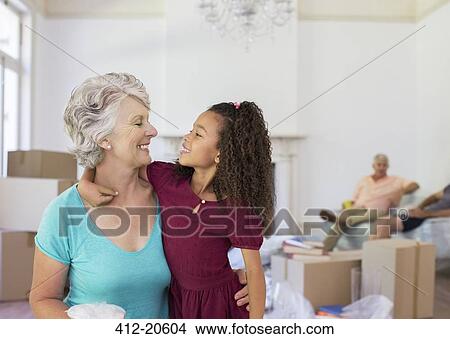 Picture - Grandmother and granddaughter hugging in living space. Fotosearch