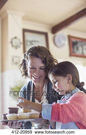 Grandmother and granddaughter placing cupcakes on tray View Large Photo Image Stock Photo - Grandmother and granddaughter placing cupcakes on tray . Fotosearch