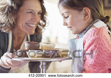 Grandmother offering granddaughter cupcakes View Large Photo Image Stock Image - Grandmother offering granddaughter cupcakes. Fotosearch