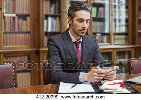 Stock Photo - Lawyer working on cell phone in chambers. Fotosearch