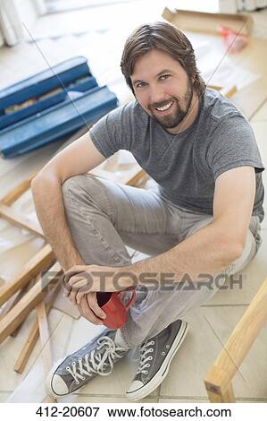 Man sitting on ground holding cup of coffee View Large Photo Image Stock Photo - Man sitting on ground holding cup of coffee. Fotosearch