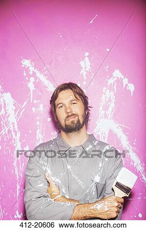 Man smiling in front of wall holding paintbrush View Large Photo Image Stock Photograph - Man smiling in front of wall holding paintbrush . Fotosearch