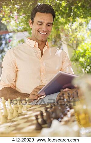 Stock Photo - Man using digital tablet outdoors near chess game. Fotosearch