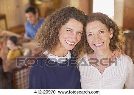 Stock Image - Mother and daughter hugging with family near. Fotosearch
