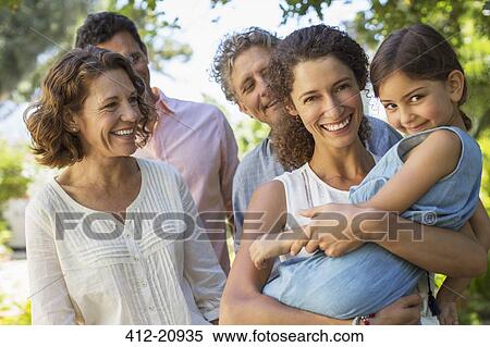 Mother carrying daughter in arms with family outdoors View Large Photo Image Stock Photography - Mother carrying daughter in arms with family outdoors . Fotosearch