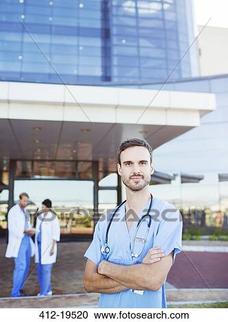 Stock Image - Nurse standing outside hospital. Fotosearch