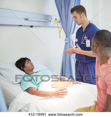 Stock Image - Nurse talking to patient in hospital room. Fotosearch