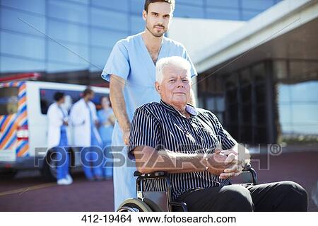Picture - Nurse wheeling patient outside hospital. Fotosearch