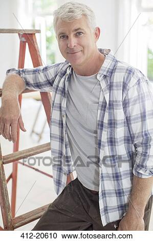Stock Image - Older man leaning on ladder. Fotosearch