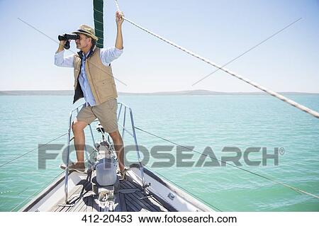 Older man looking out binoculars on edge of boat View Large Photo Image Stock Image - Older man looking out binoculars on edge of boat . Fotosearch