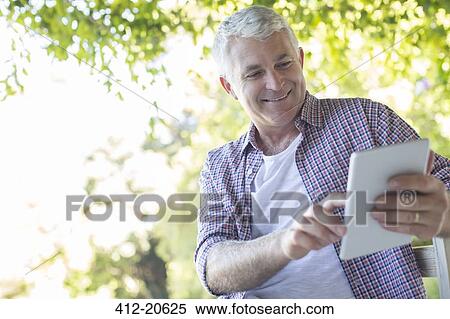Older man using digital tablet outdoors View Large Photo Image Stock Photography - Older man using digital tablet outdoors. Fotosearch