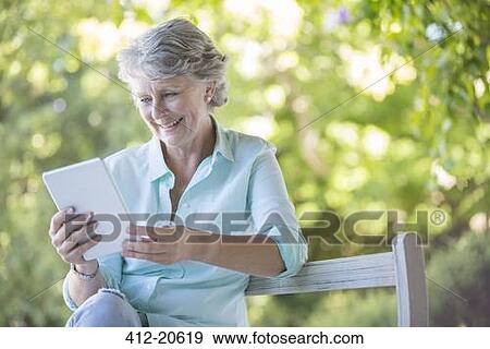 Older woman using digital tablet outdoors View Large Photo Image Stock Photo - Older woman using digital tablet outdoors. Fotosearch