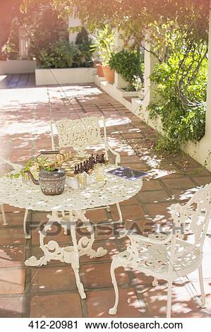 Stock Image - Outdoor dinning table on backyard patio. Fotosearch