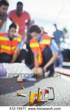 Stock Image - Paramedics examining injured girl on street. Fotosearch