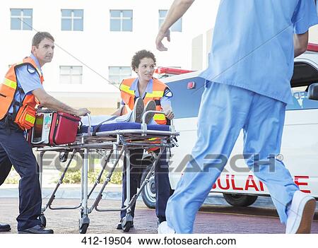 Paramedics wheeling patient in hospital parking lot View Large Photo Image Picture - Paramedics wheeling patient in hospital parking lot. Fotosearch