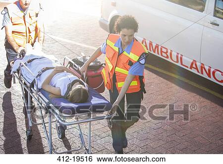 Stock Photograph - Paramedics wheeling patient in hospital parking lot. Fotosearch