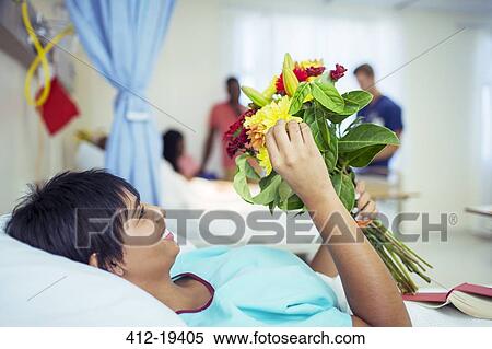 Stock Photography - Patient admiring bouquet of flowers in hospital room. Fotosearch