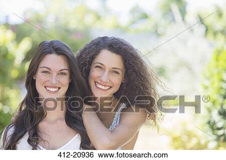 Stock Photograph - Sisters smiling together outdoors. Fotosearch