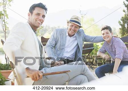 Picture - Three generations of men relaxing outdoors. Fotosearch