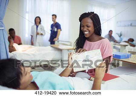 Woman giving card to boyfriend in hospital room View Large Photo Image Stock Image - Woman giving card to boyfriend in hospital room. Fotosearch
