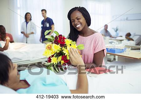 Woman giving mother bouquet of flowers in hospital View Large Photo Image Stock Image - Woman giving mother bouquet of flowers in hospital. Fotosearch