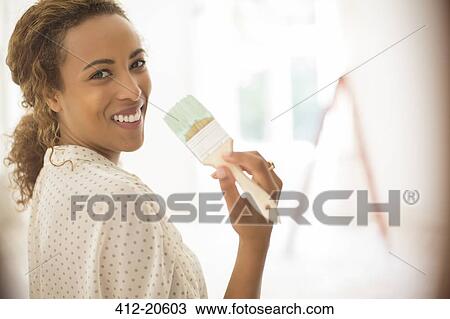 Woman holding paint brush in living space View Large Photo Image Stock Image - Woman holding paint brush in living space. Fotosearch