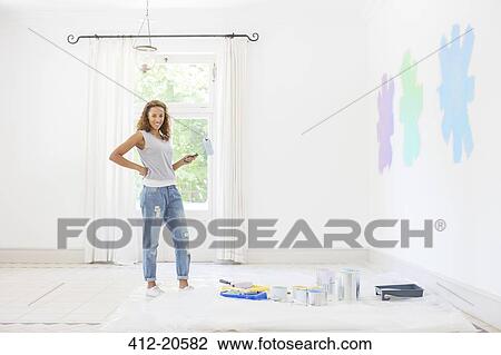 Stock Image - Woman painting walls in living space. Fotosearch