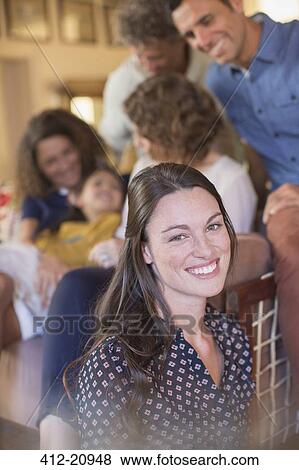 Stock Photo - Woman smiling in living space with family . Fotosearch