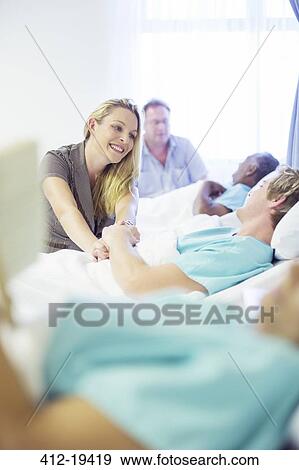 Stock Photo - Woman talking to boyfriend in hospital room. Fotosearch