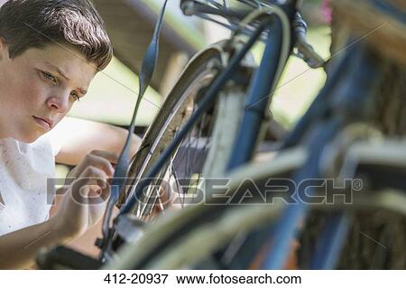 Stock Photo - Young boy examining bicycle outdoors. Fotosearch