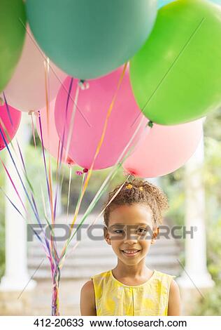 Stock Image - Young girl holding bunch of balloons. Fotosearch