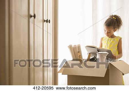 Stock Photography - Young girl reading book near moving box . Fotosearch