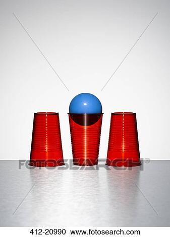 Stock Image - Blue ball in middle of three red cups. Fotosearch