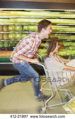Stock Photo - Blurred view of couple playing in grocery store. Fotosearch