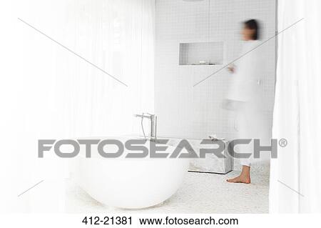 Stock Image - Blurred view of woman walking in modern bathroom. Fotosearch