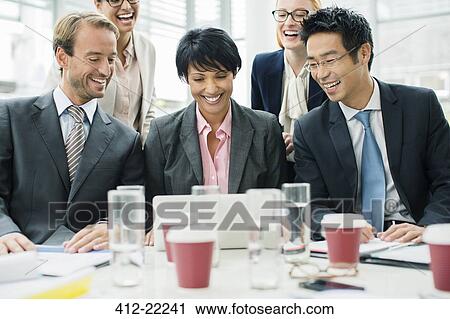 Business people gathered around laptop at table View Large Photo Image Stock Image - Business people gathered around laptop at table. Fotosearch