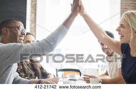 Business people high fiving at meeting in cafe View Large Photo Image Stock Image - Business people high fiving at meeting in cafe. Fotosearch