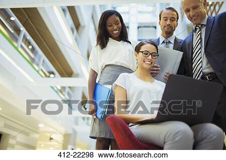 Business people looking at laptop in office building View Large Photo Image Stock Photo - Business people looking at laptop in office building. Fotosearch