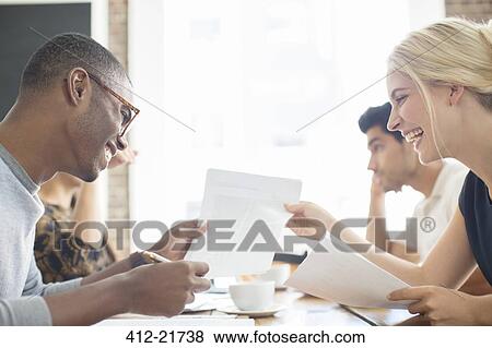 Business people looking through paperwork together in cafe View Large Photo Image Stock Photo - Business people looking through paperwork together in cafe . Fotosearch