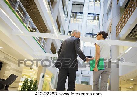 Business people shaking hands in office building View Large Photo Image Stock Image - Business people shaking hands in office building. Fotosearch