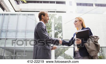 Business people shaking hands outside office building View Large Photo Image Stock Photo - Business people shaking hands outside office building. Fotosearch