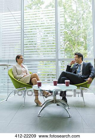 Business people talking at coffee table in office building View Large Photo Image Stock Photo - Business people talking at coffee table in office building. Fotosearch