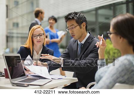 Business people talking at table outside of office building View Large Photo Image Stock Image - Business people talking at table outside of office building. Fotosearch