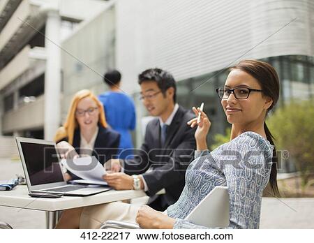 Business people talking at table outside office building View Large Photo Image Stock Photo - Business people talking at table outside office building. Fotosearch
